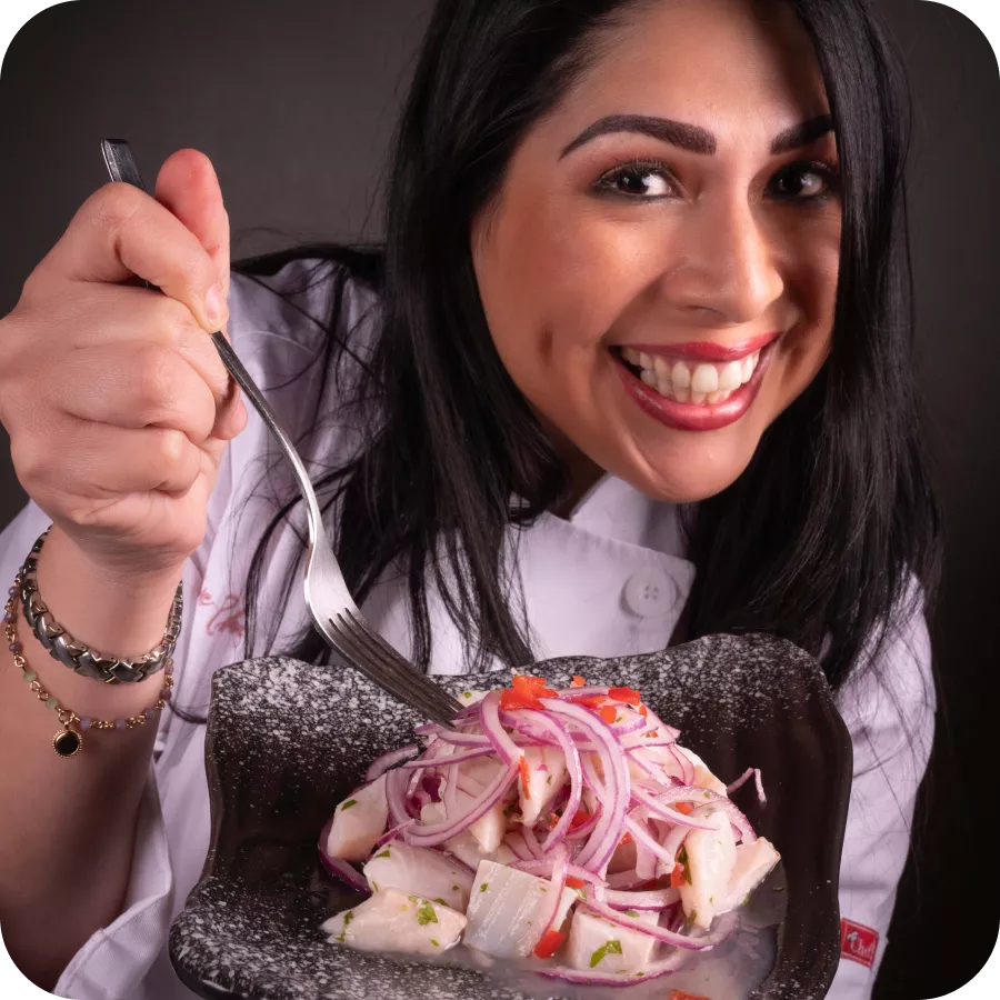 Smiling chef holding a fork and a plate of Peruvian ceviche with red onions